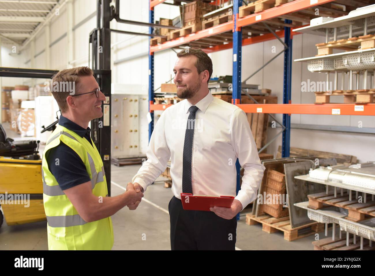 Lavoratore e manager in un magazzino nel settore logistico - stretta di mano la mattina per iniziare a lavorare in un nuovo lavoro Foto Stock