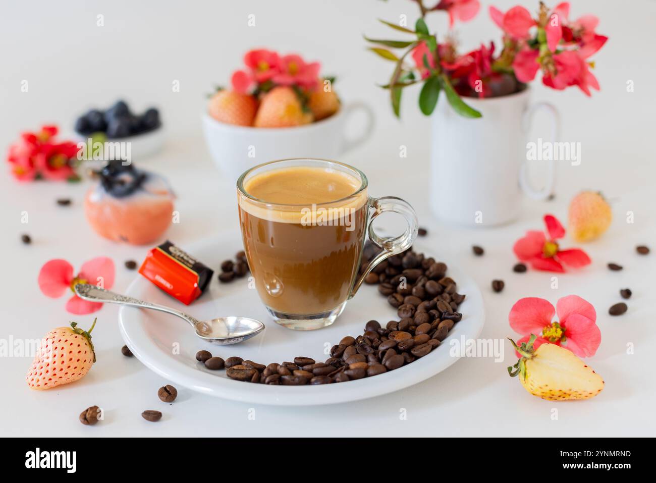Tazza di caffè con chicchi di caffè, fragole e fiori: Natura morta piatta Foto Stock
