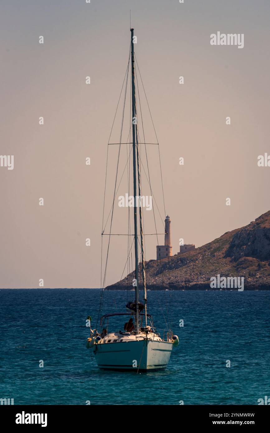 Barca a vela all'ancora di fronte al faro di Punta Palascia. Foto Stock