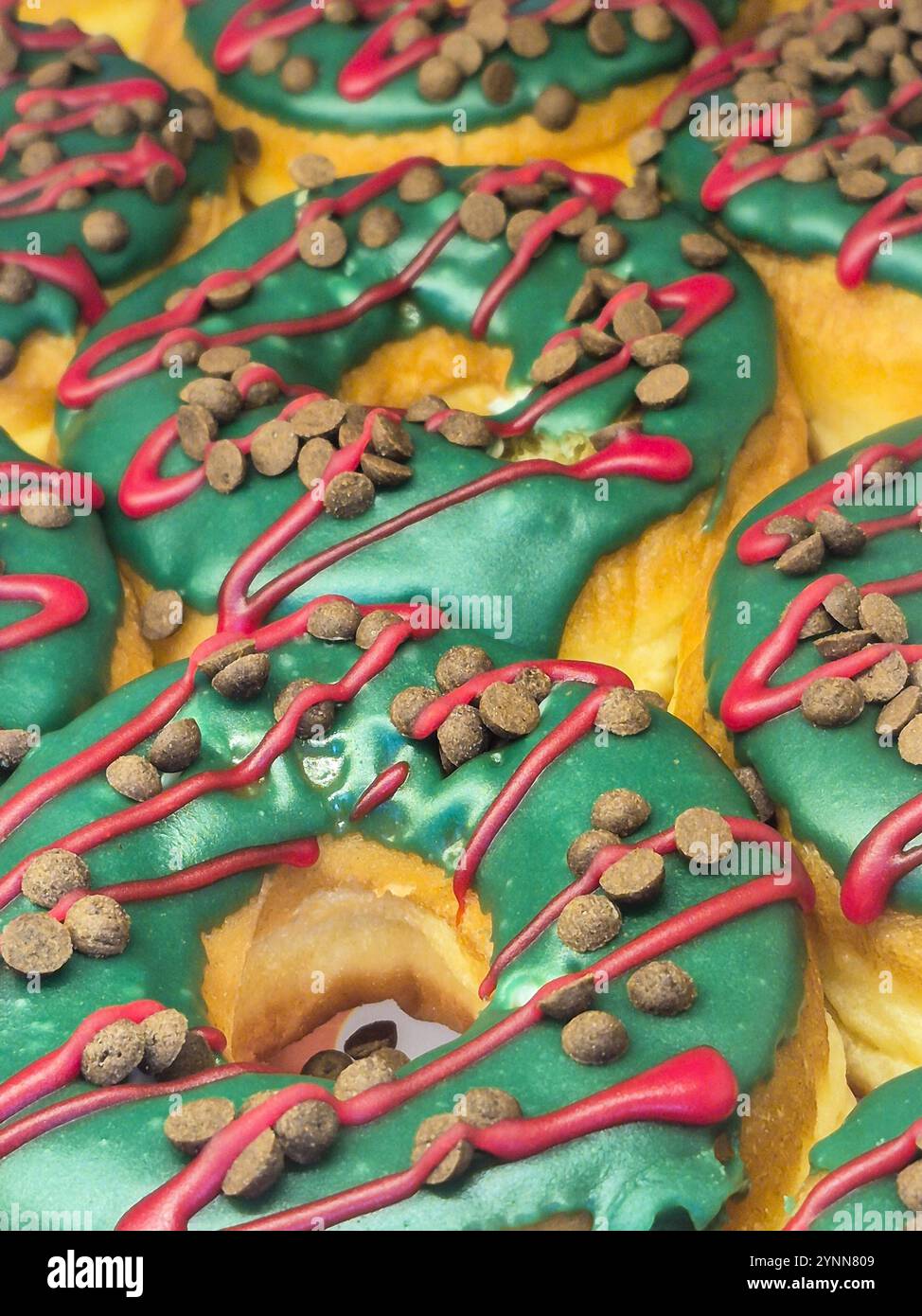 Goiania, Goias, Brasile – 25 novembre 2024: Una serie di ciambelle decorate con glassa verde e gocce di cioccolato. In mostra per la vendita. Foto Stock
