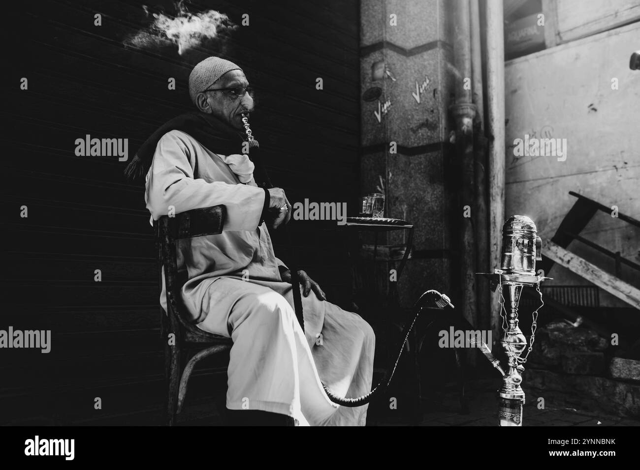 Un vecchio che fuma narghilè in una vecchia caffetteria Foto Stock