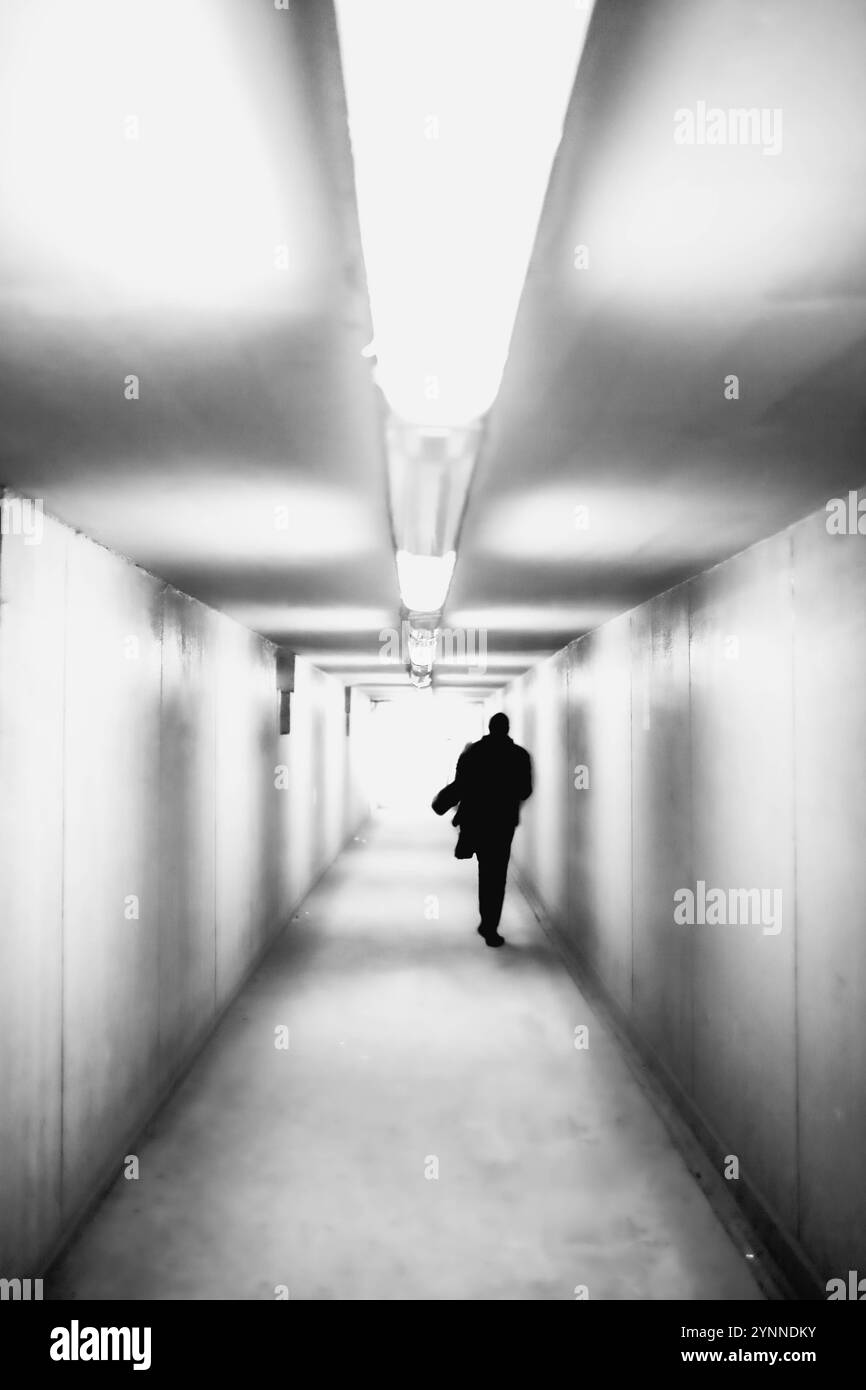 La silhouette di un uomo che cammina in un tunnel Foto Stock