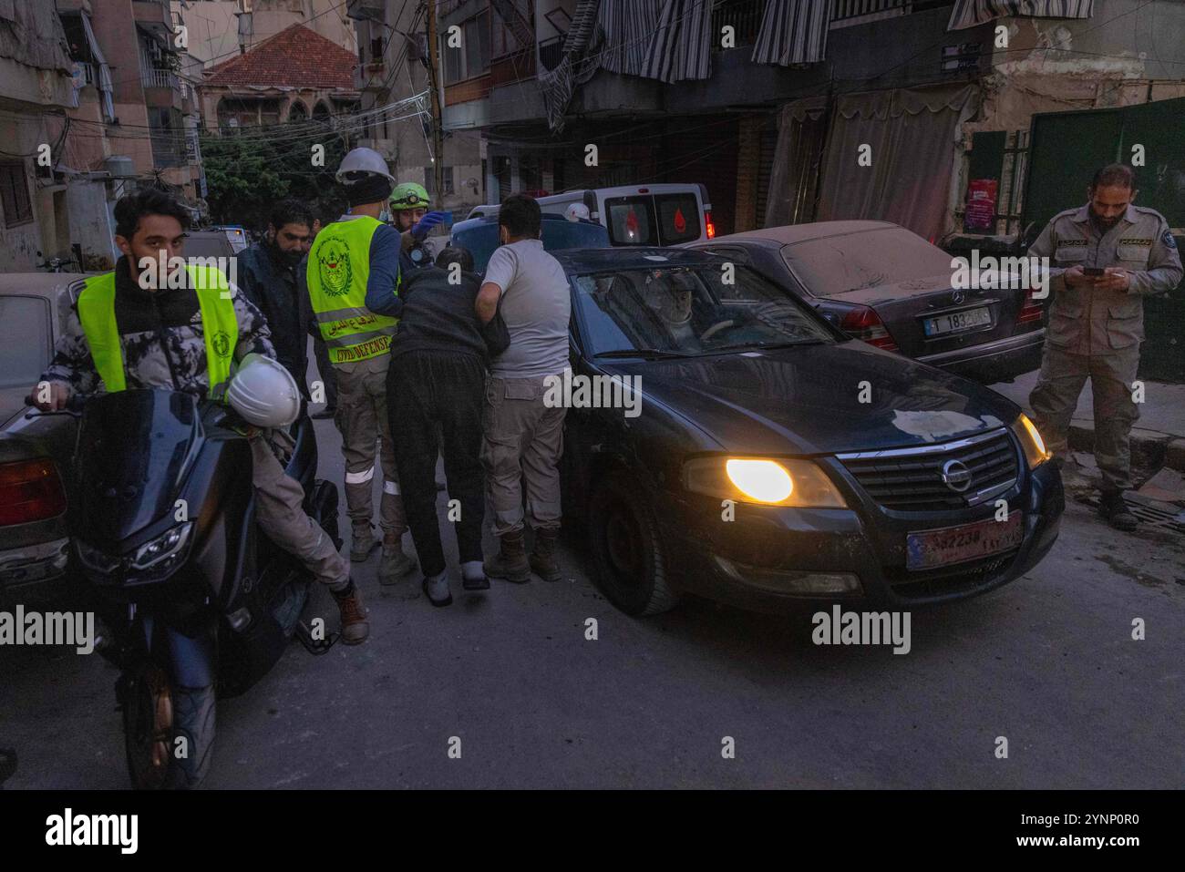Beirut, Libano. 26 novembre 2024. I lavoratori della difesa civile assistono un anziano su un veicolo in modo che possa evacuare l'area dopo un attacco israeliano che ha livellato un edificio residenziale di Beirut centrale il 26 novembre 2024 a Beirut, in Libano. Le strade erano caotiche, dato che la gente portava sacchi di evacuazione e cercava le mappe per trovare luoghi sicuri dove fuggire. Sono state sentite sparatorie anche quando la gente ha avvertito i loro vicini quando Israele minacciava luoghi. Le forze israeliane hanno ripetutamente attaccato Beirut e in tutto il Libano prima di un possibile cessate il fuoco. (Credit Image: © Daniel Carde/ZUMA Press Wire) SOLO PER USO EDITORIALE! Non per Foto Stock