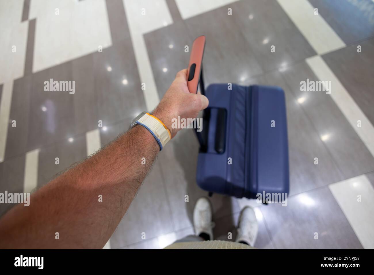 Prospettiva del viaggiatore che tiene una maniglia per valigia in un terminal aeroportuale Foto Stock