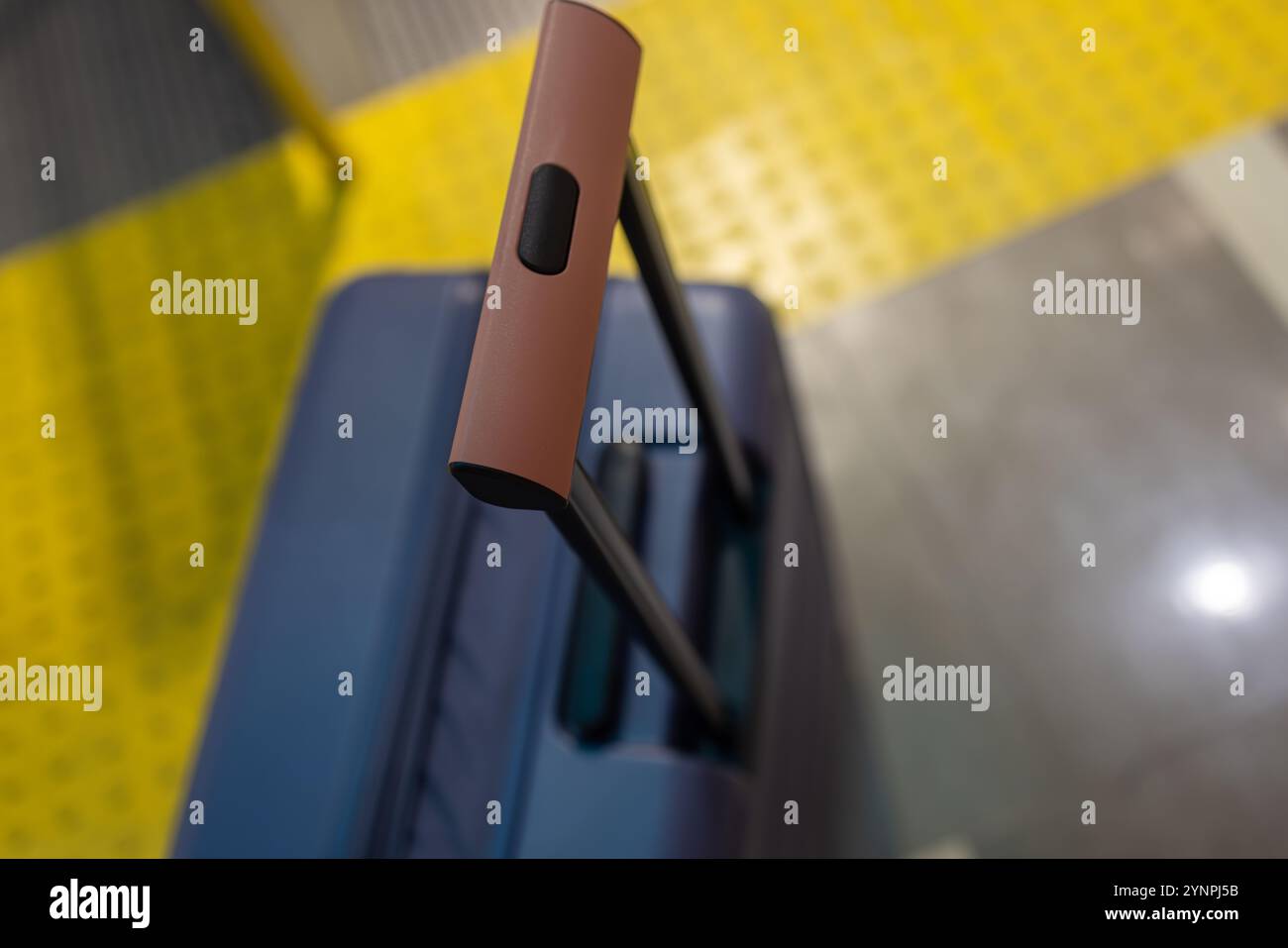 Primo piano di una maniglia per valigia su una piattaforma con pavimentazione tattile gialla Foto Stock