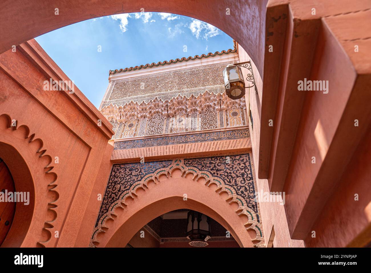 Vista esterna della Madrasa di Ben Youssef, caratterizzata da un arco e ornati dettagli Ochre a Marrakech, Marocco Foto Stock