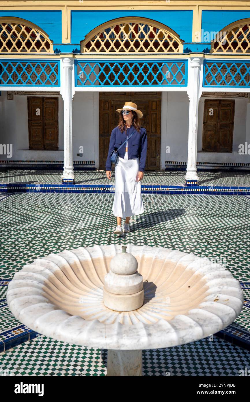 Giovane donna dai capelli scuri in Navy Blazer e gonna bianca in posa accanto alla fontana principale di Bahia Palace Marrakech, Marocco Foto Stock