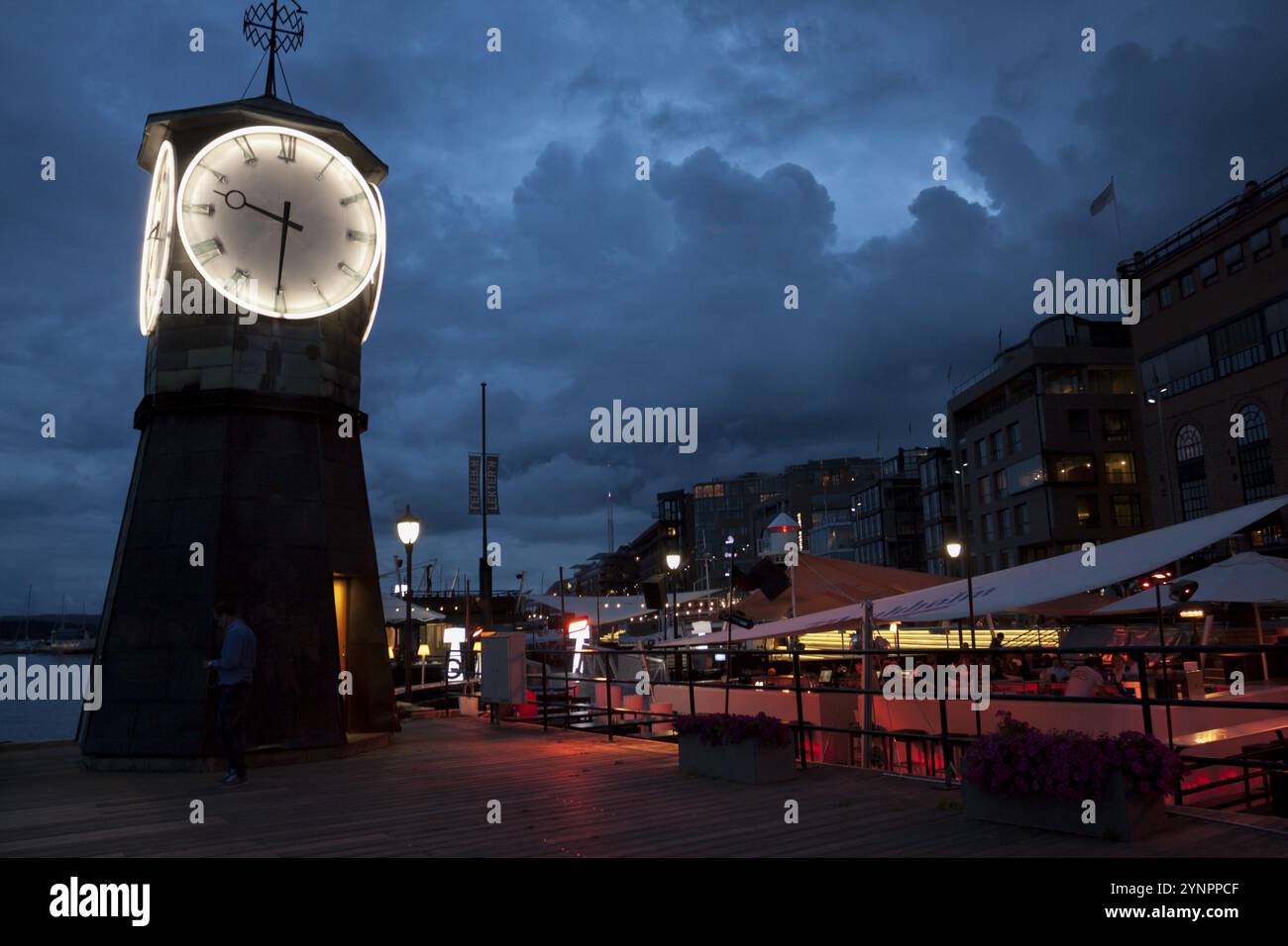 Torre dell'orologio e bel ristorante al mistico crepuscolo nel porto. Oslo, Ostlandet. Norvegia Foto Stock