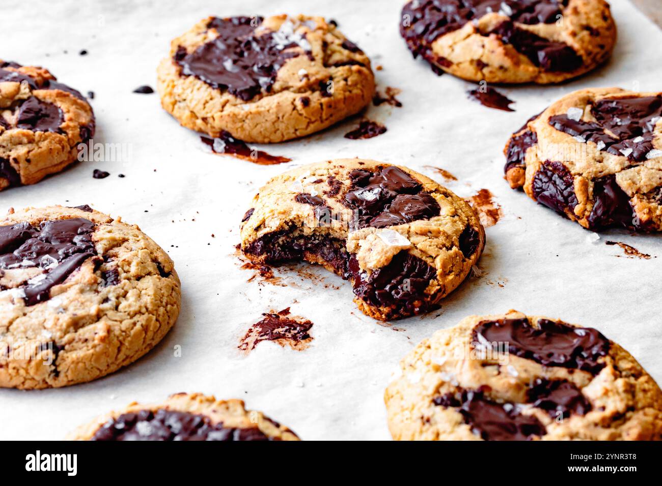 Un assortimento di biscotti appena sfornati con pezzi di cioccolato su carta pergamena. Foto Stock