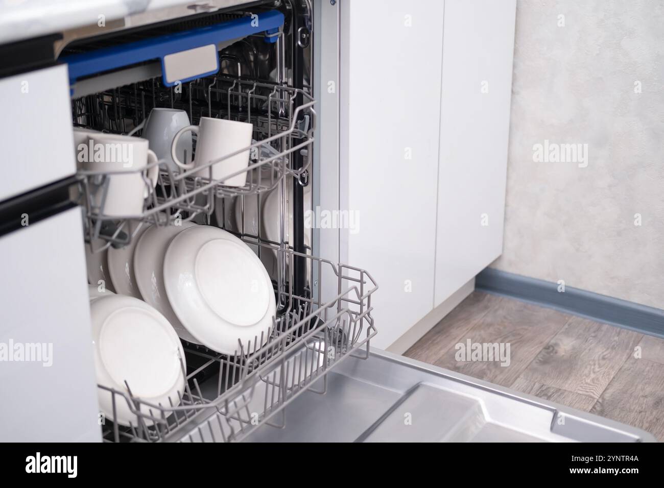 Sportello della lavastoviglie incorporato aperto. Cucina con elettrodomestici incorporati. Piatti e piatti sono lavabili in lavastoviglie. Foto Stock