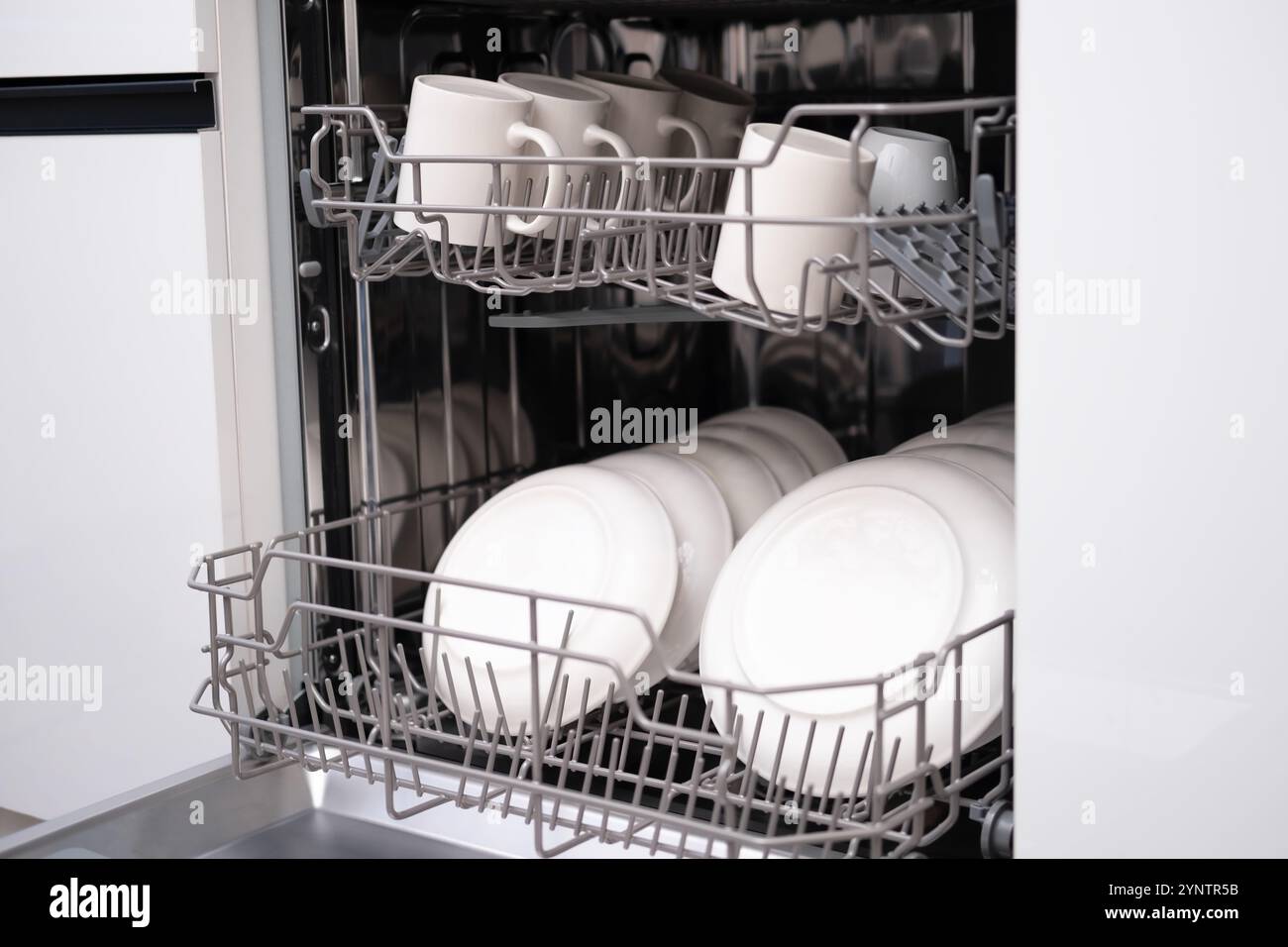 Sportello della lavastoviglie incorporato aperto. Cucina con elettrodomestici incorporati. Piatti e piatti sono lavabili in lavastoviglie. Foto Stock