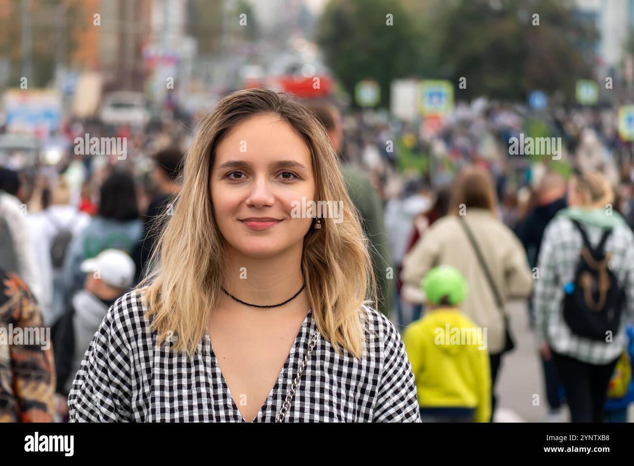 donna sola davanti alla folla dall'altra parte della strada. Una ragazza va contro il movimento della folla durante il giorno in una grande città. Foto Stock