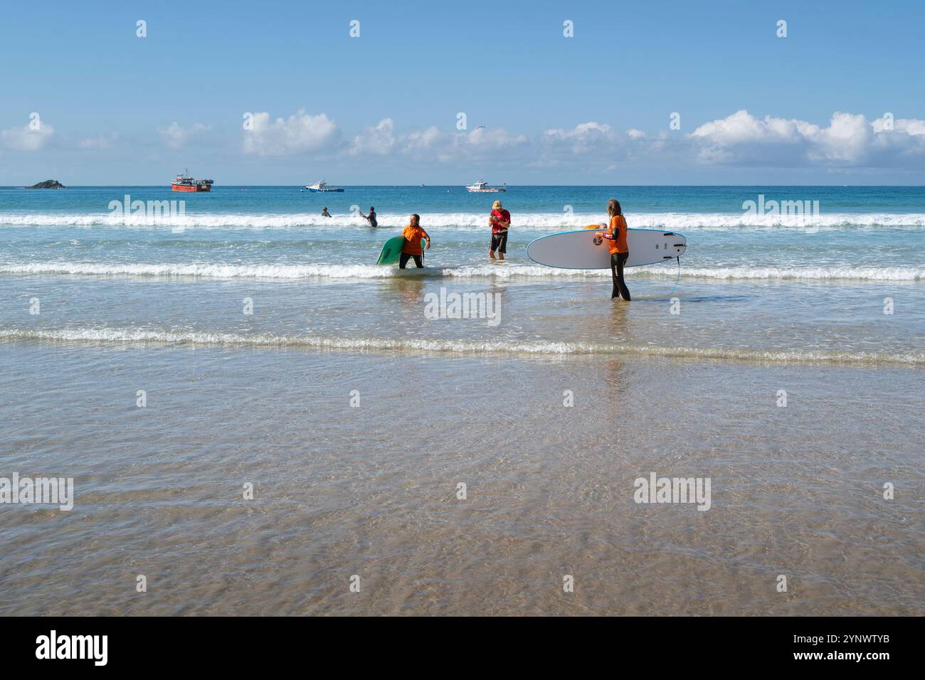 Turisti che terminano una lezione di surf con il loro istruttore a Towan Beach a Newquay in Cornovaglia nel Regno Unito. Foto Stock