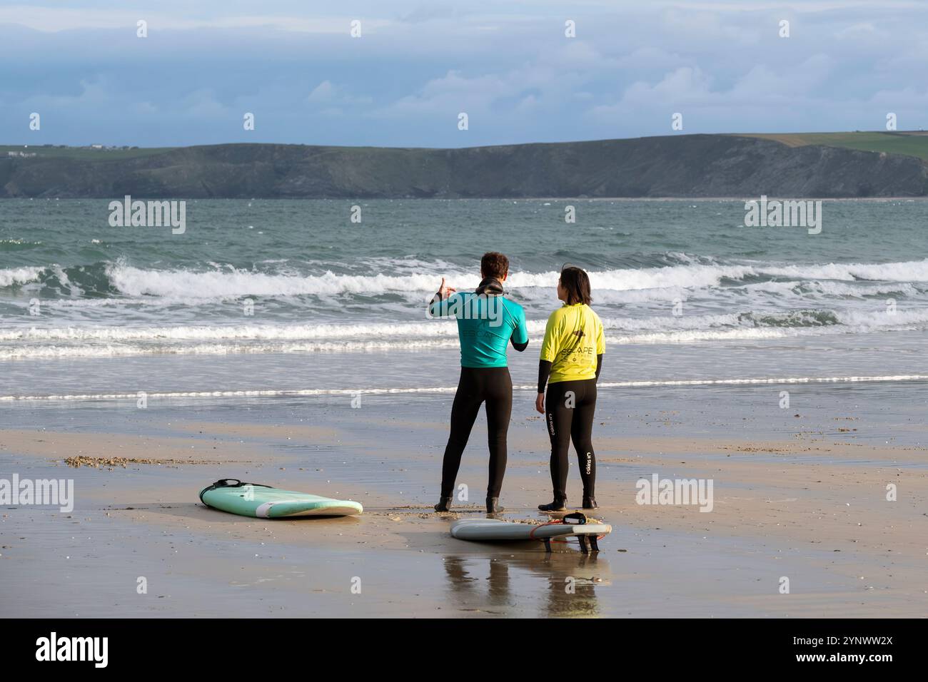 Un istruttore di surf della Escape Surfing School che tiene una lezione di surf uno a uno con un principiante a Towan Beach a Newquay in Cornovaglia, Regno Unito. Foto Stock