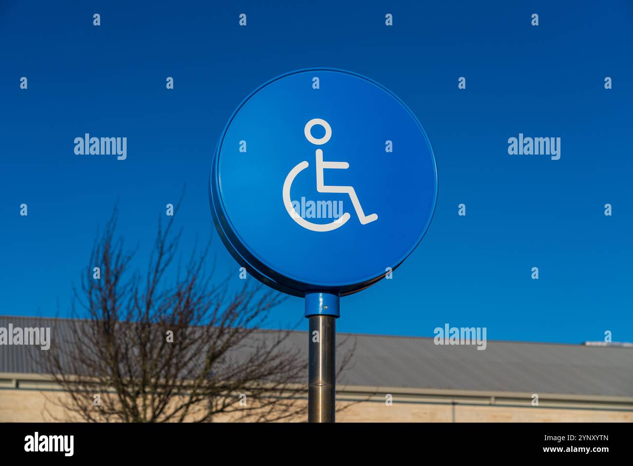 Cartellone blu per il parcheggio per disabili con l'immagine di una persona su sedia a rotelle Foto Stock