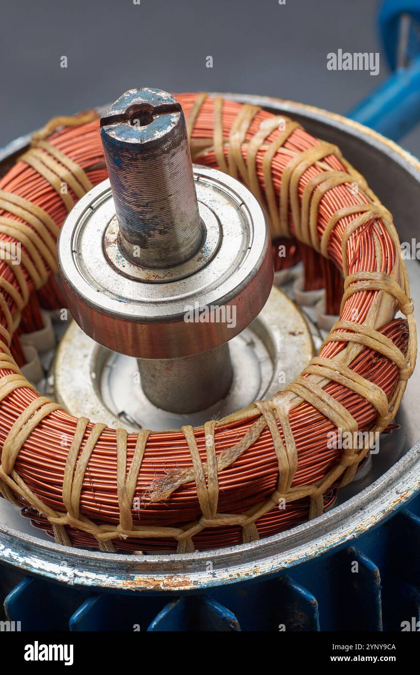 primo piano di avvolgimenti in rame avvolti intorno al nucleo metallico del motore elettrico smontato, generano un campo magnetico per azionare il motore Foto Stock