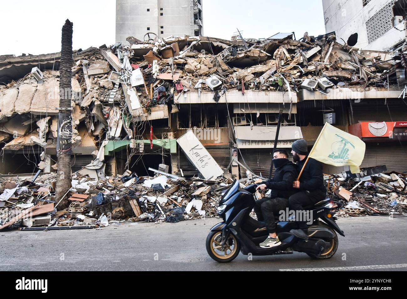 Beirut, Libano. 27 novembre 2024. I libanesi hanno issato la bandiera di Hezbollah, mentre restituiscono le loro case con veicoli dopo che l'accordo di cessate il fuoco tra Israele e Libano è entrato in vigore nella regione di Dahieh a Beirut, Libano, il 27 novembre 2024. Foto di FADEL ITANI/UPI. Crediti: UPI/Alamy Live News Foto Stock