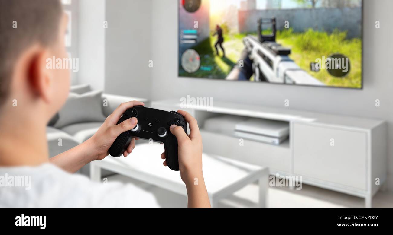 Ragazzo che gioca a un gioco per console su una TV in salotto, con uno sparatutto in prima persona, che mette in evidenza il concetto di esperienza di gioco su console coinvolgente Foto Stock