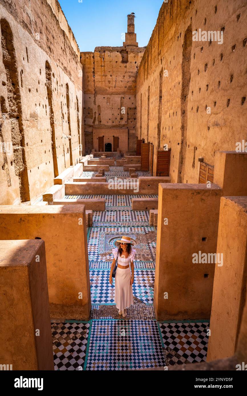 Giovane donna dai capelli scuri in abito bianco e cappello in posa al Palazzo El Badii di Marrakech con piastrelle colorate, Marrakech Foto Stock