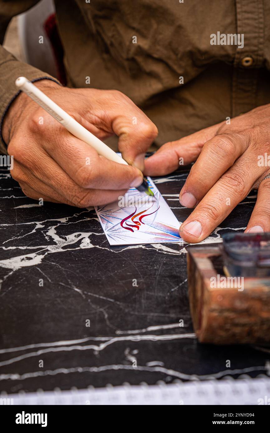 Mani di un uomo che decora un segnalibro per le strade di Marrakech, Marocco Foto Stock
