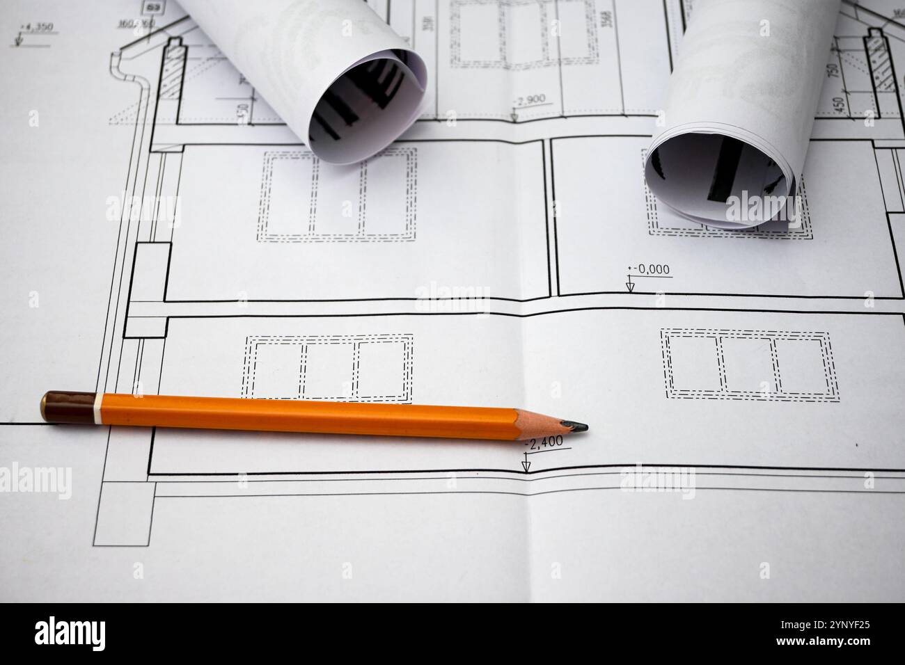 Disegni architettonici che mostrano le planimetrie della casa, accompagnati da una matita e da progetti arrotolati, simboleggiano il processo di progettazione e costruzione. Foto Stock