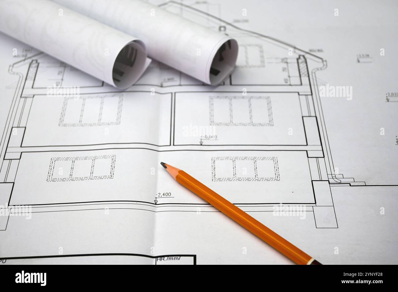 Disegni architettonici che mostrano le planimetrie della casa, accompagnati da una matita e da progetti arrotolati, simboleggiano il processo di progettazione e costruzione. Foto Stock