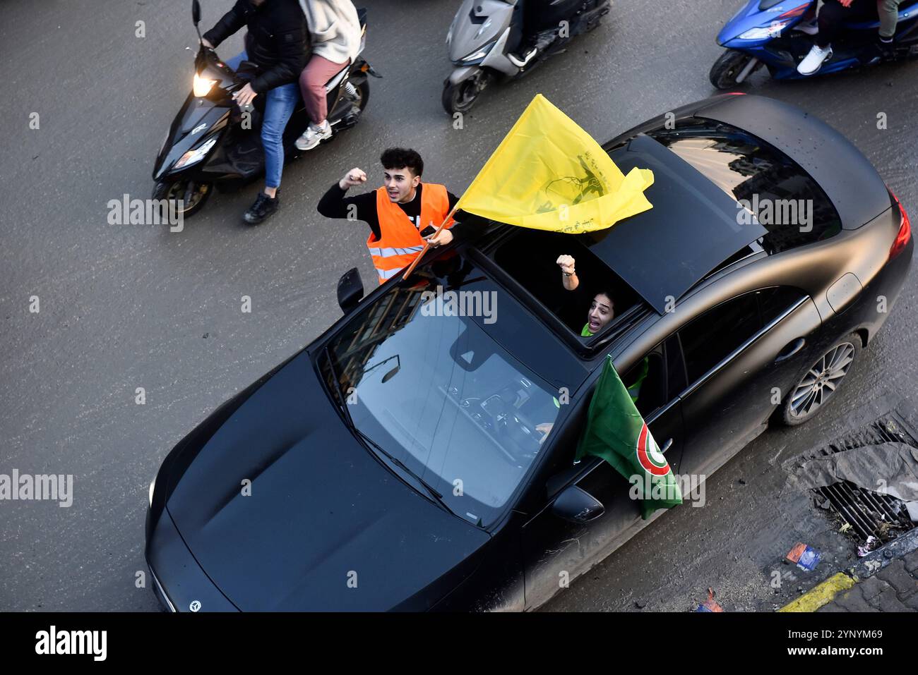 Beirut, Libano. 27 novembre 2024. I libanesi hanno issato la bandiera di Hezbollah, tenendo striscioni, restituiscono le loro case con veicoli dopo che l'accordo di cessate il fuoco tra Israele e Libano è entrato in vigore nella regione di Dahieh a Beirut, Libano, il 27 novembre 2024. Foto di FADEL ITANI/UPI. Crediti: UPI/Alamy Live News Foto Stock