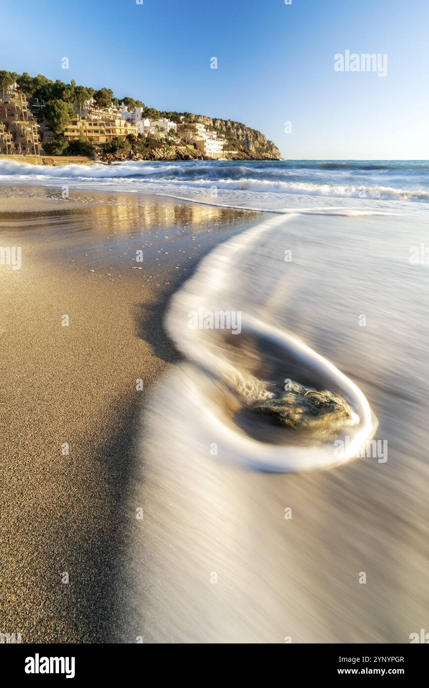 Acqua che scorre sulla spiaggia dell'isola di maiorca in spagna al tramonto Foto Stock