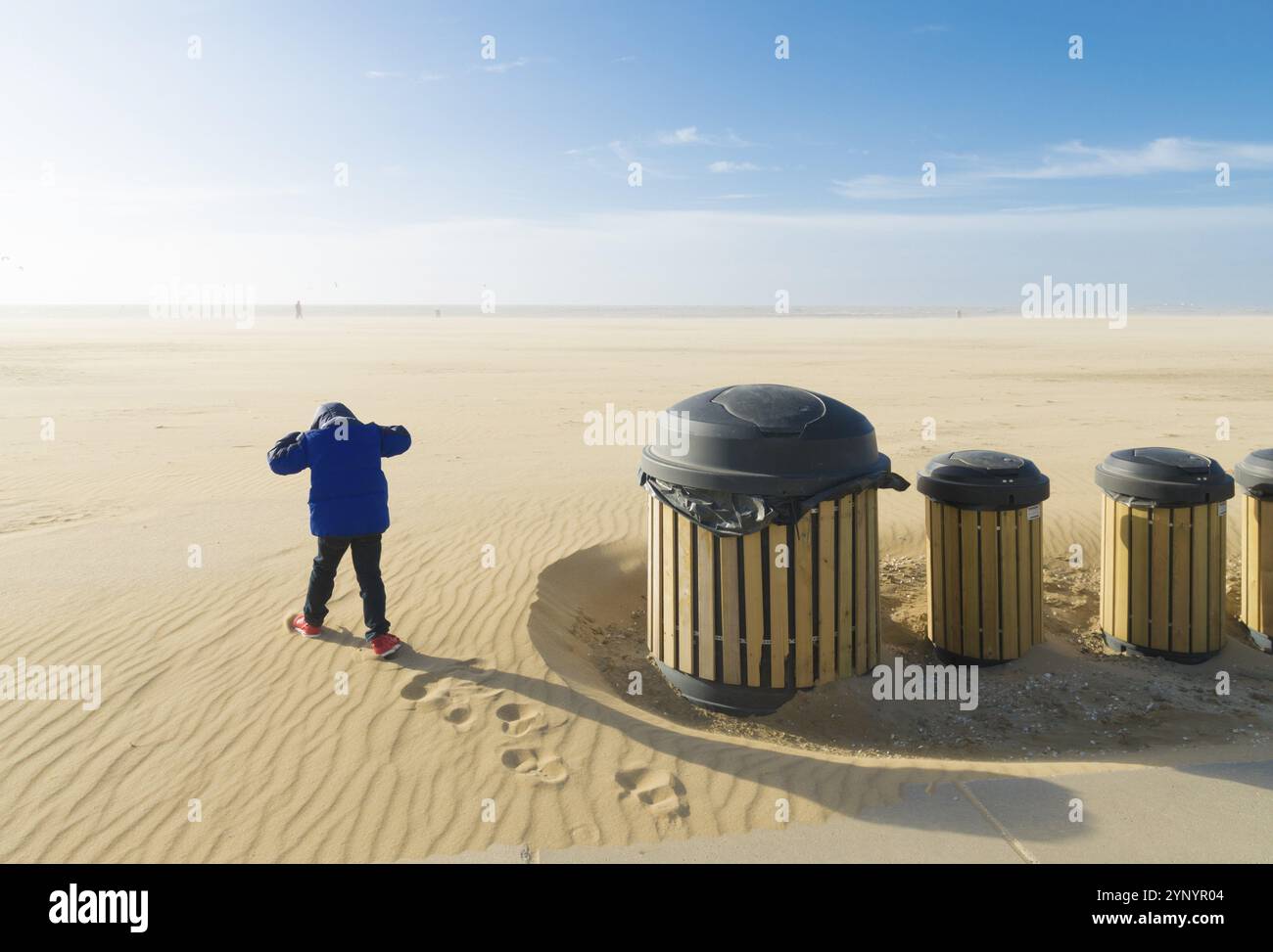 Ragazzino che si prepara per una corsa a vento su una spiaggia desolata Foto Stock