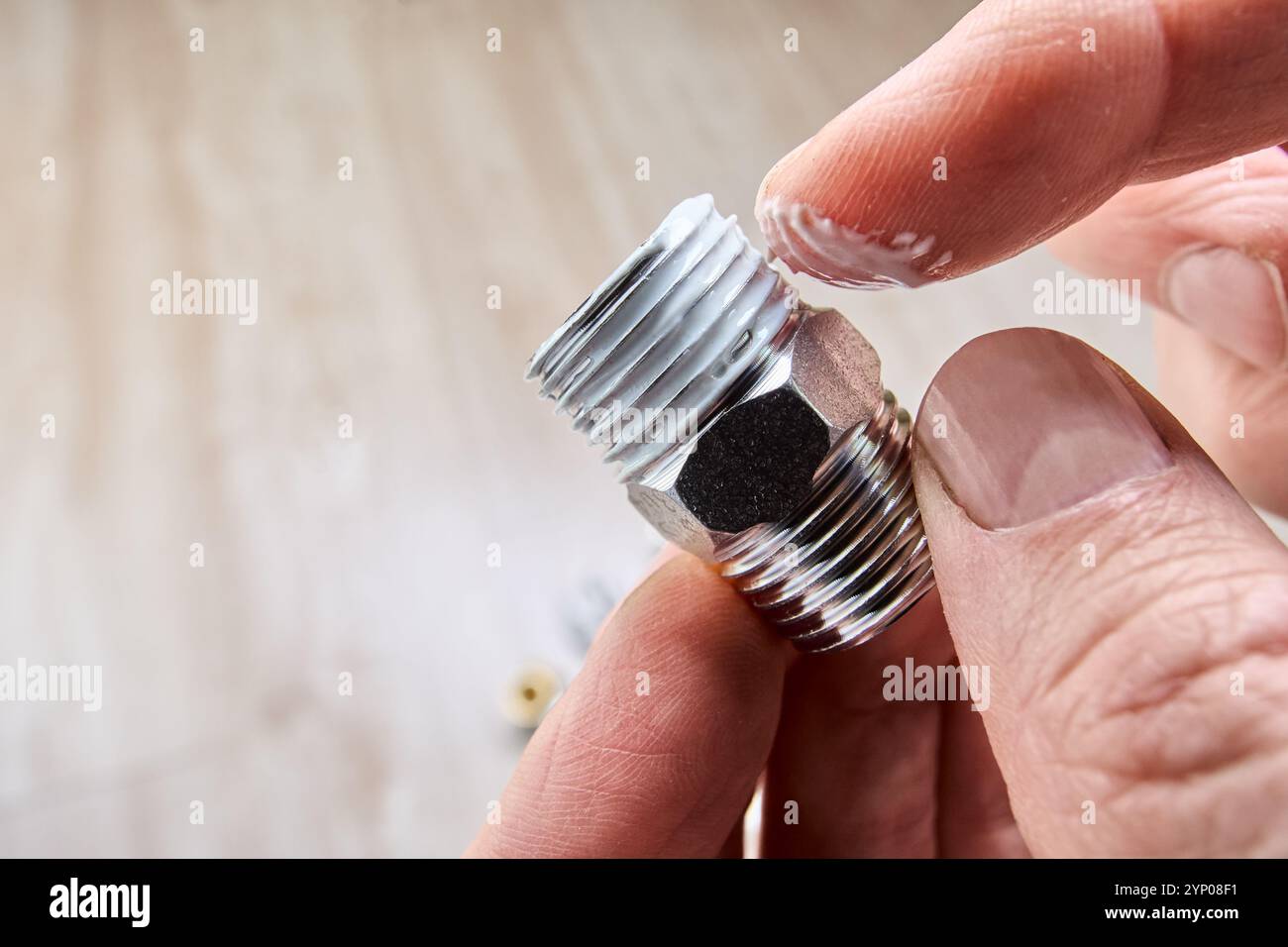 Applicare del sigillante a pasta per il collegamento a tenuta ermetica prima di avvolgere la canapa sulla filettatura del raccordo del tubo. Foto Stock