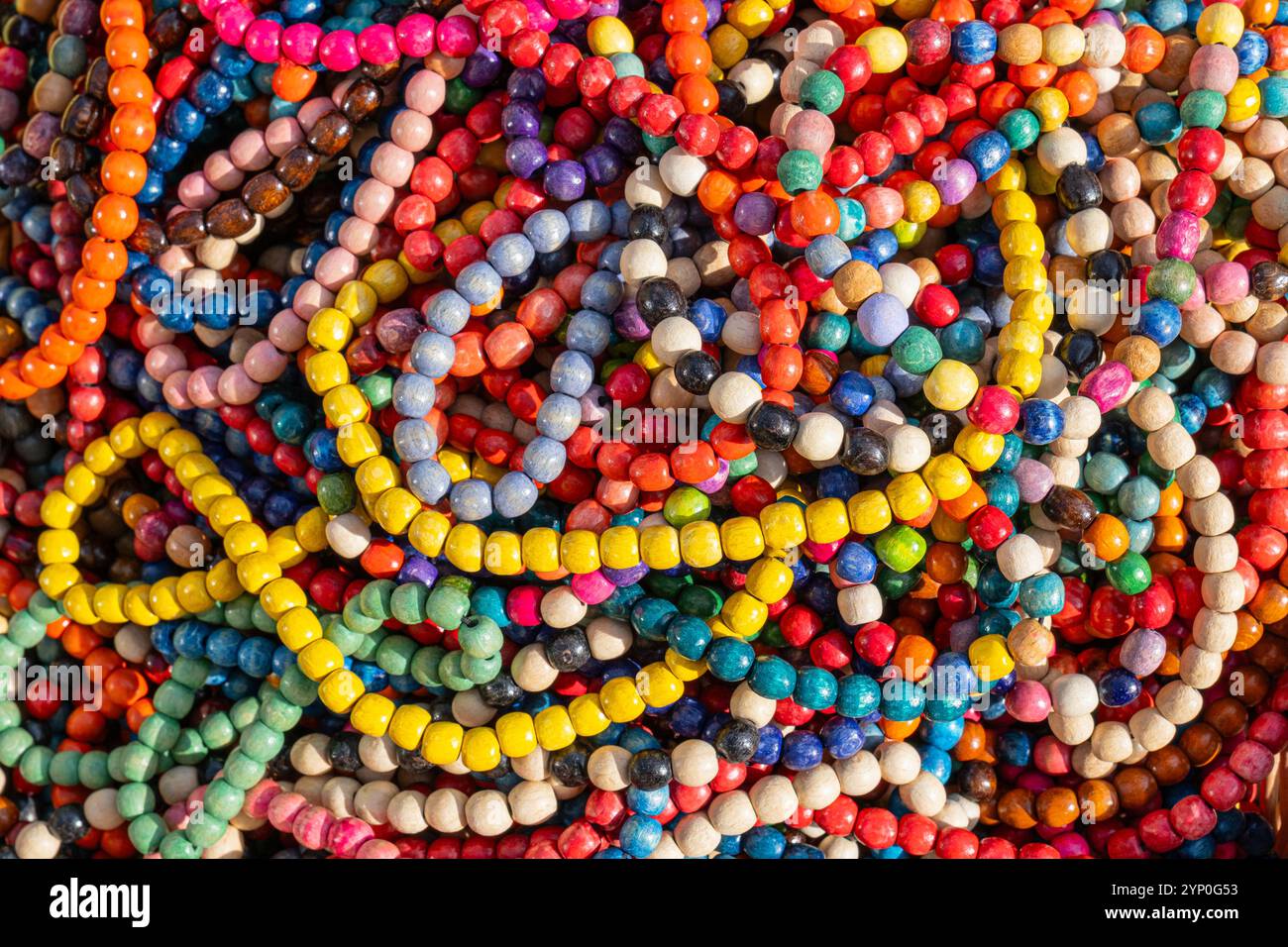 un mucchio di perle di legno colorate utilizzate per realizzare collane tradizionali viene mostrato da vicino, illustrando materiali vivaci e culturali per gioielli Foto Stock