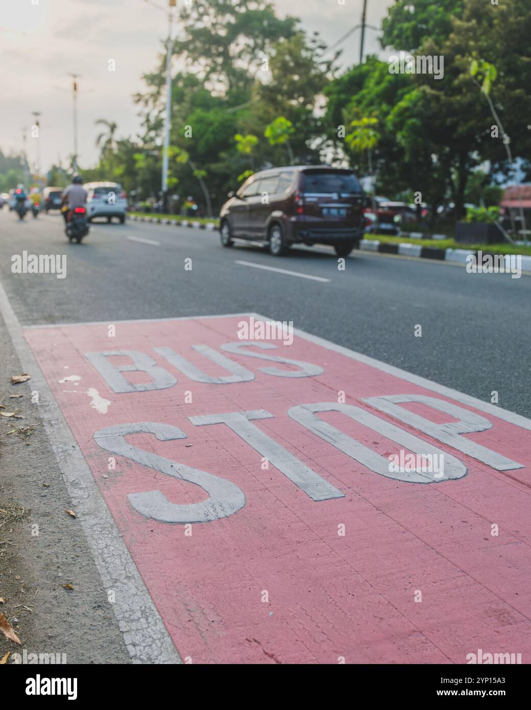 Balikpapan, Indonesia - 3 settembre 2024. Un segnale di fermata dell'autobus dipinto sulla strada con il traffico in movimento sullo sfondo. Foto Stock
