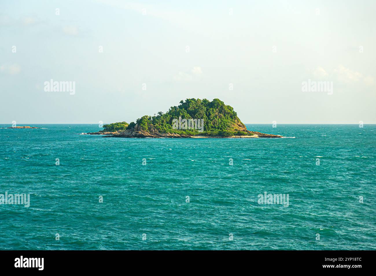 Un'isola solitaria e bella nel mare con le onde. Bellissima isola rocciosa sopra il cielo blu Foto Stock