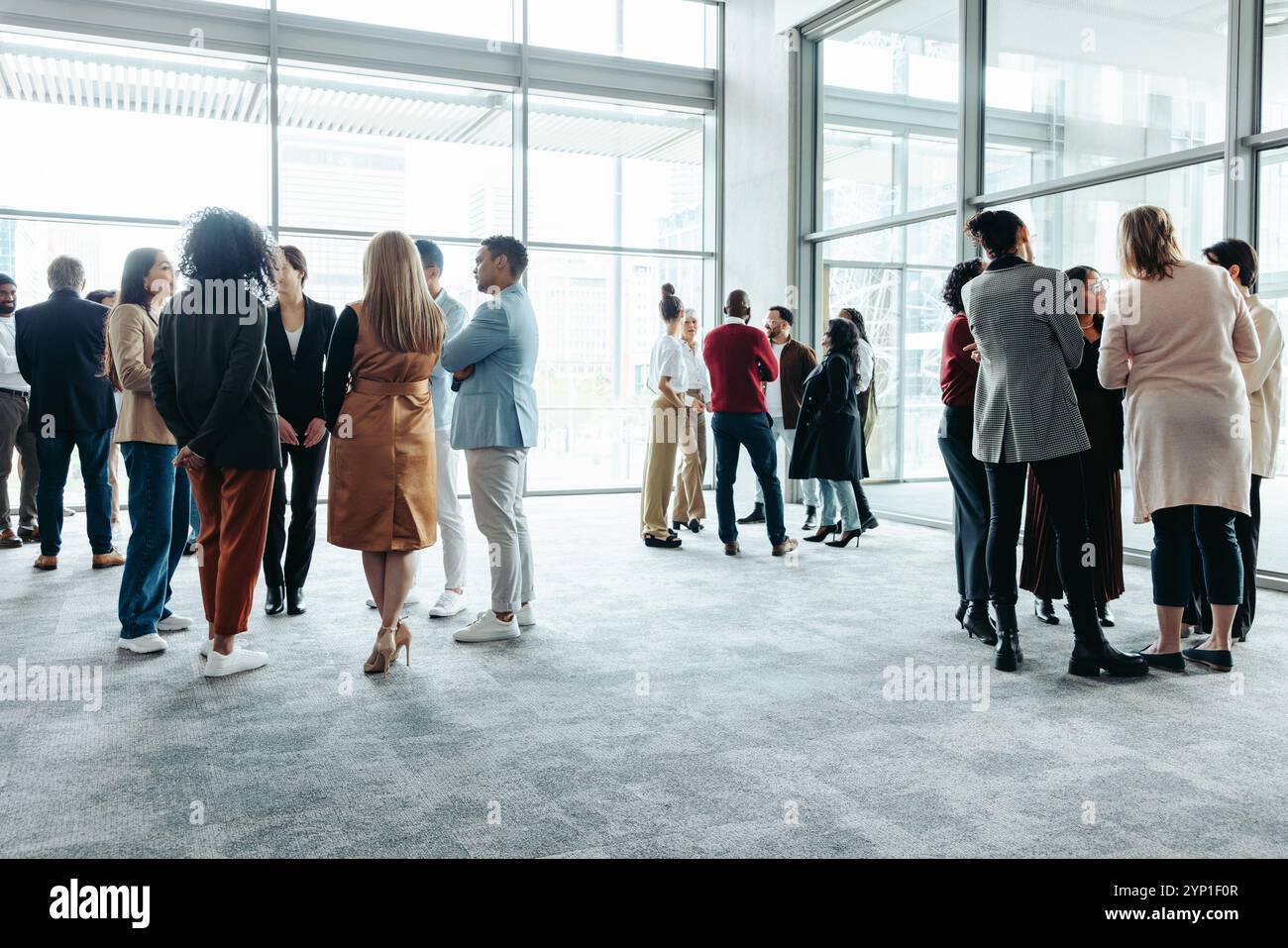 Un gruppo di persone che si mette in contatto e partecipa a discussioni in occasione di una conferenza aziendale. Una folla diversificata impegnata in conversazioni informali in un ambiente moderno Foto Stock