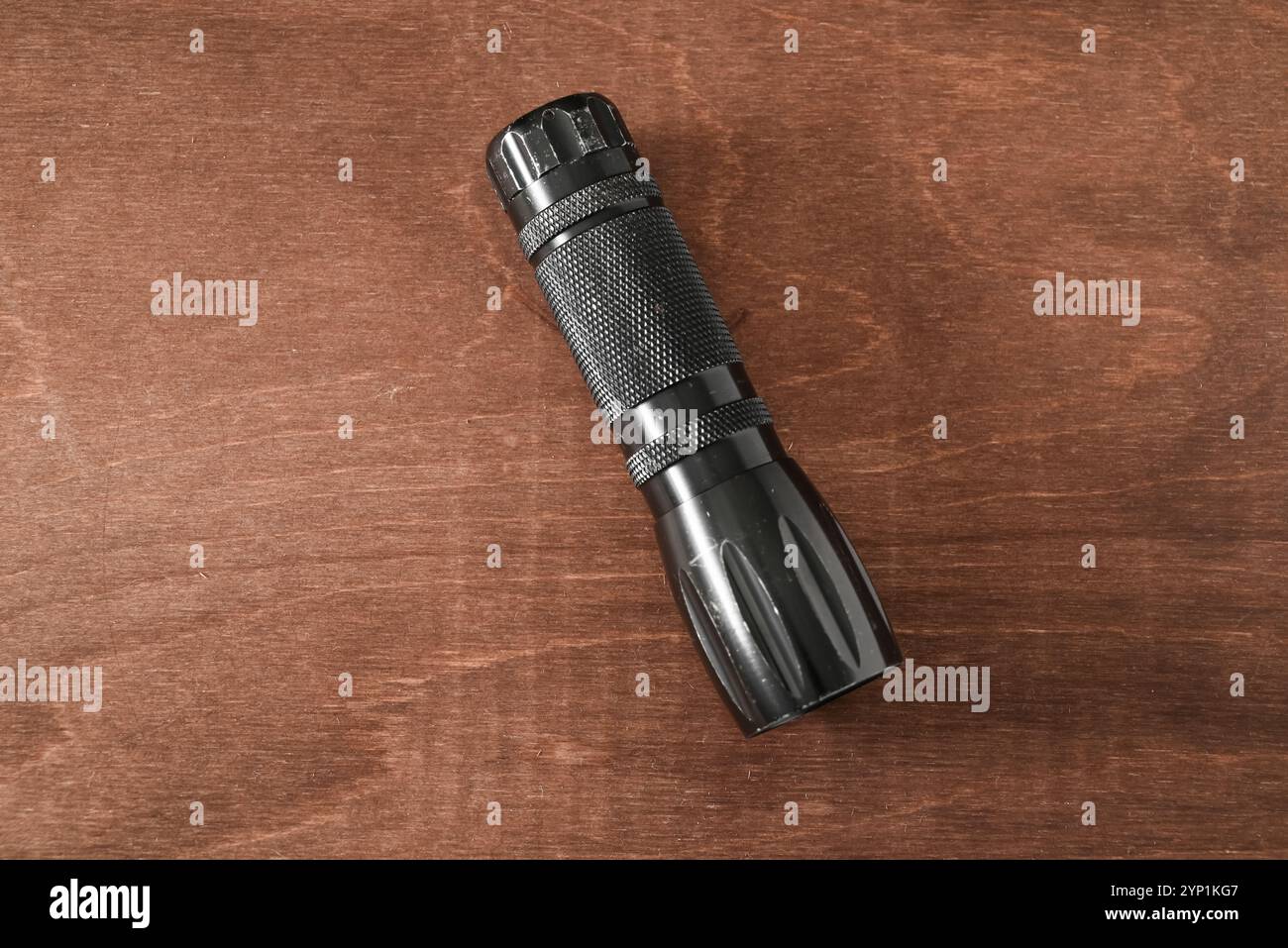 piccola ma potente torcia o torcia elettrica ben usata su un tavolo in legno Foto Stock