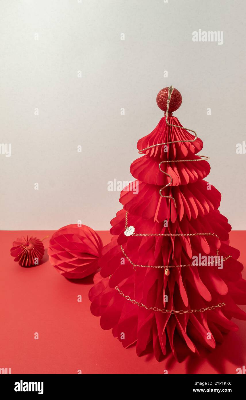 Collana di canapa dorata su un albero a nido d'ape di Natale di carta rossa. Foto Stock