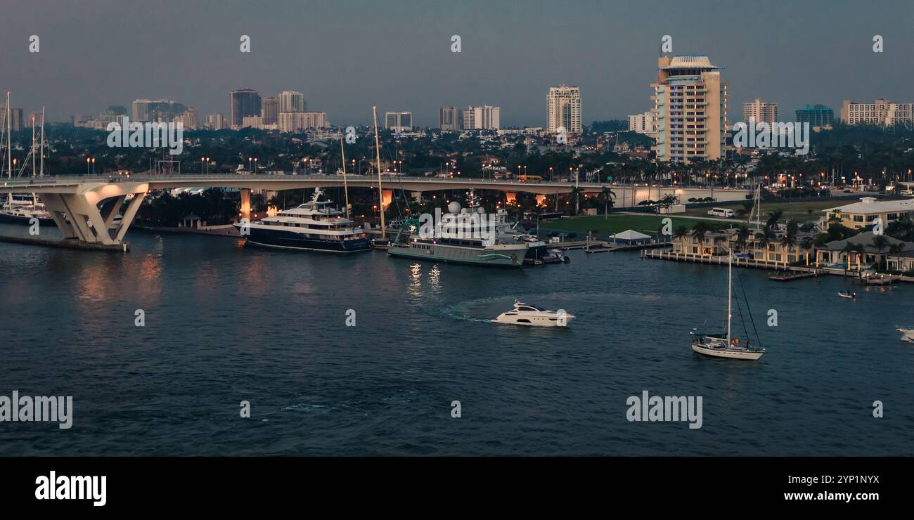 Fort Lauderdale, USA - 29 dicembre 2017: Vista serale di yacht e barche attraccate vicino a un ponte con lo skyline della città sullo sfondo. Foto Stock