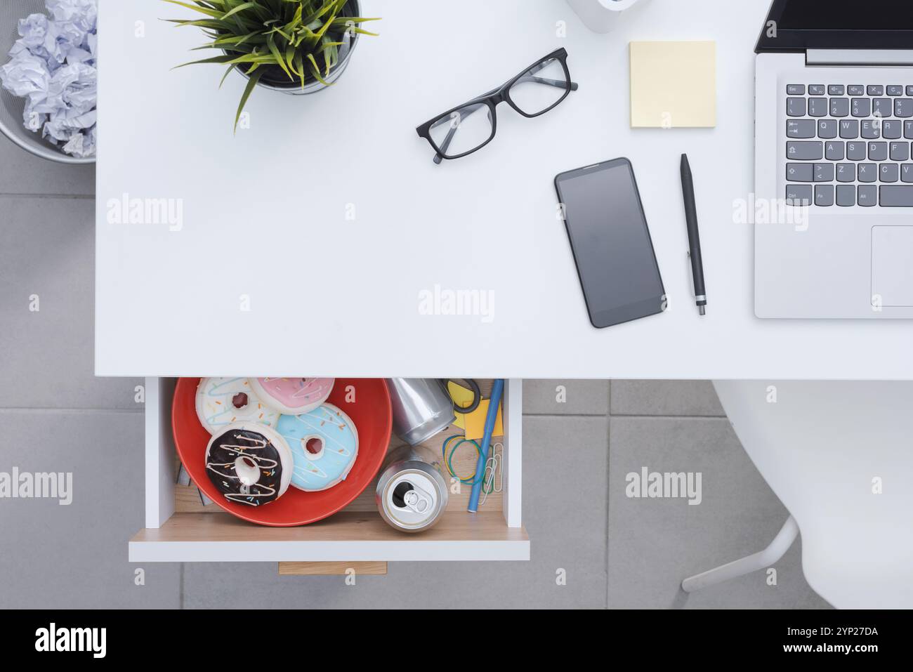 Scrivania ordinata e cassetto aperto con cibo spazzatura e disordine all'interno, spazio per le copie Foto Stock