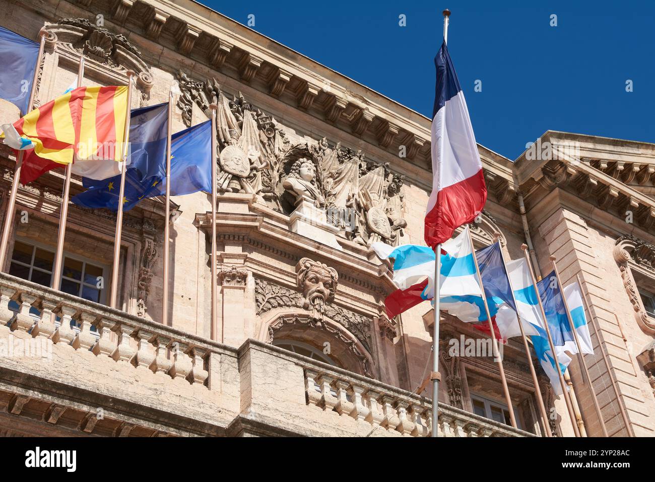 Marsiglia. Francia - 27 novembre 2024: Il municipio di Marsiglia, con bandiere francesi e intricati dettagli architettonici, adagiato su un cielo blu brillante, Foto Stock