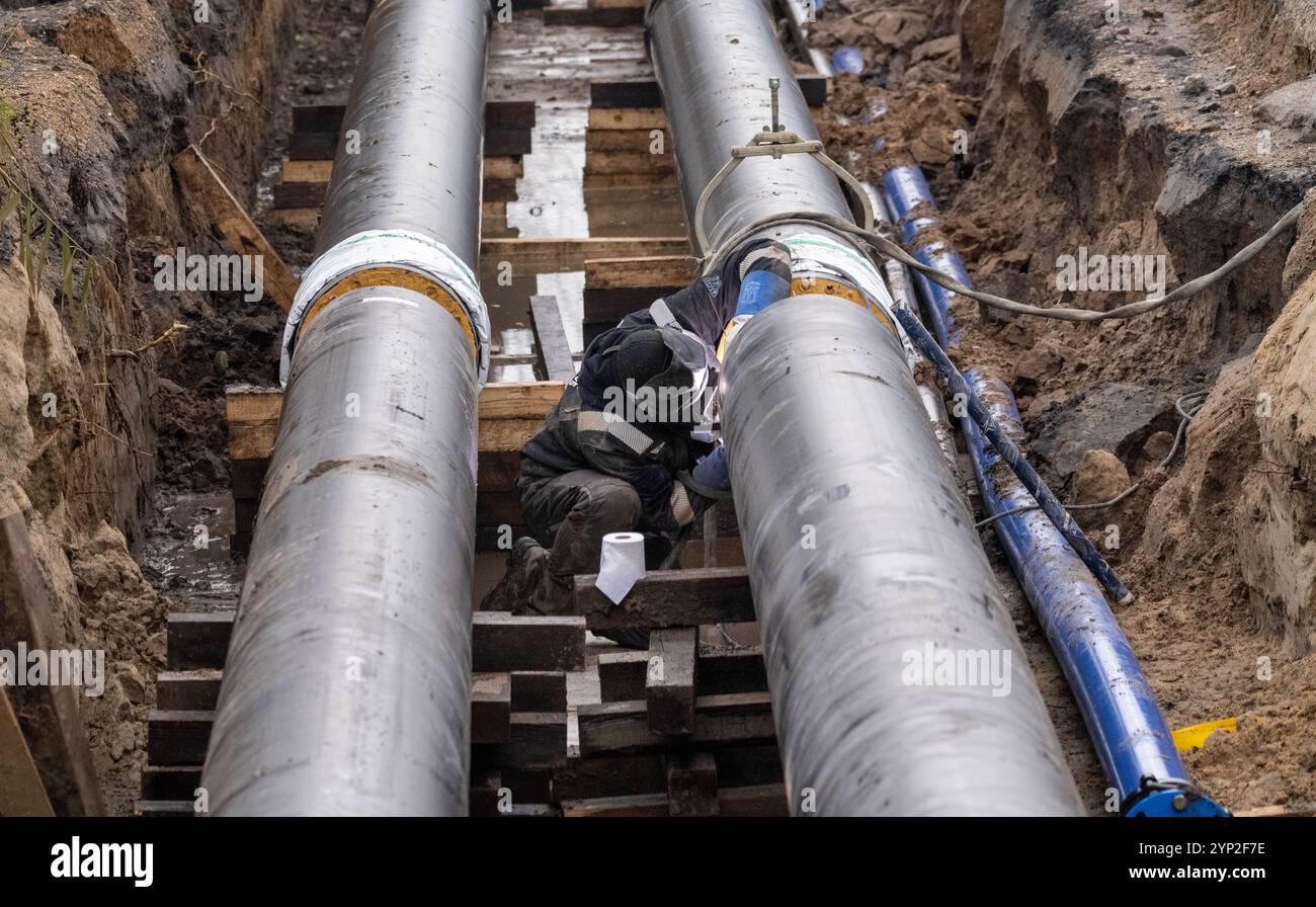 28 novembre 2024, Meclemburgo-Pomerania occidentale, Stralsund: Vista del cantiere per un gasdotto di teleriscaldamento per il distretto Knieper/Grünhufe a Stralsund. Sono attualmente in corso lavori di costruzione di una centrale combinata di calore ed energia elettrica (iKWK) con un sistema solare termico a Stralsund. In futuro, l'impianto genererà oltre 11 GWh di calore all'anno e coprirà quindi oltre il 10% dei requisiti di rete dell'area di teleriscaldamento Knieper/Grünhufe, l'area residenziale con il maggior numero di abitanti a Stralsund. La messa in funzione e l'alimentazione nella rete sono previste per la metà del 2025 Foto Stock