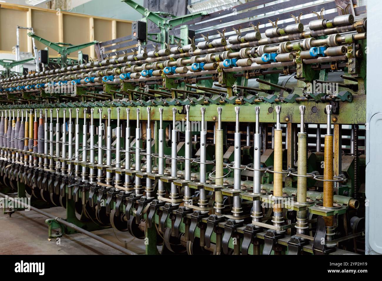 Una vecchia macchina per la filatura nel negozio di tessitura di una fabbrica tessile abbandonata Foto Stock