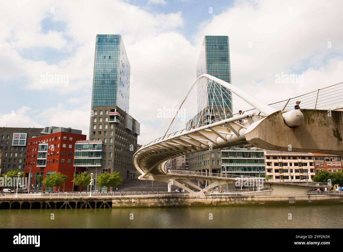 Zubizuri, ponte pedonale ad arco lungo il fiume Nervion, progettato dall'architetto Santiago Calatrava, con le torri gemelle Isozaki Atea Foto Stock