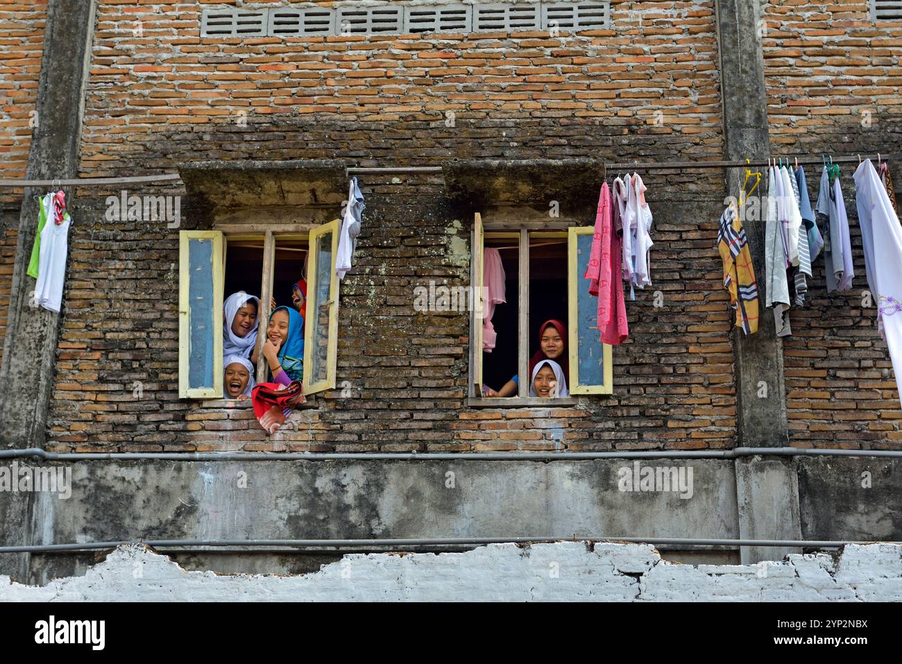 Ragazze scolastiche alla finestra di un dormitorio delle scuole superiori, Lasem, isola di Giava, Indonesia, Sud-est asiatico, Asia Foto Stock