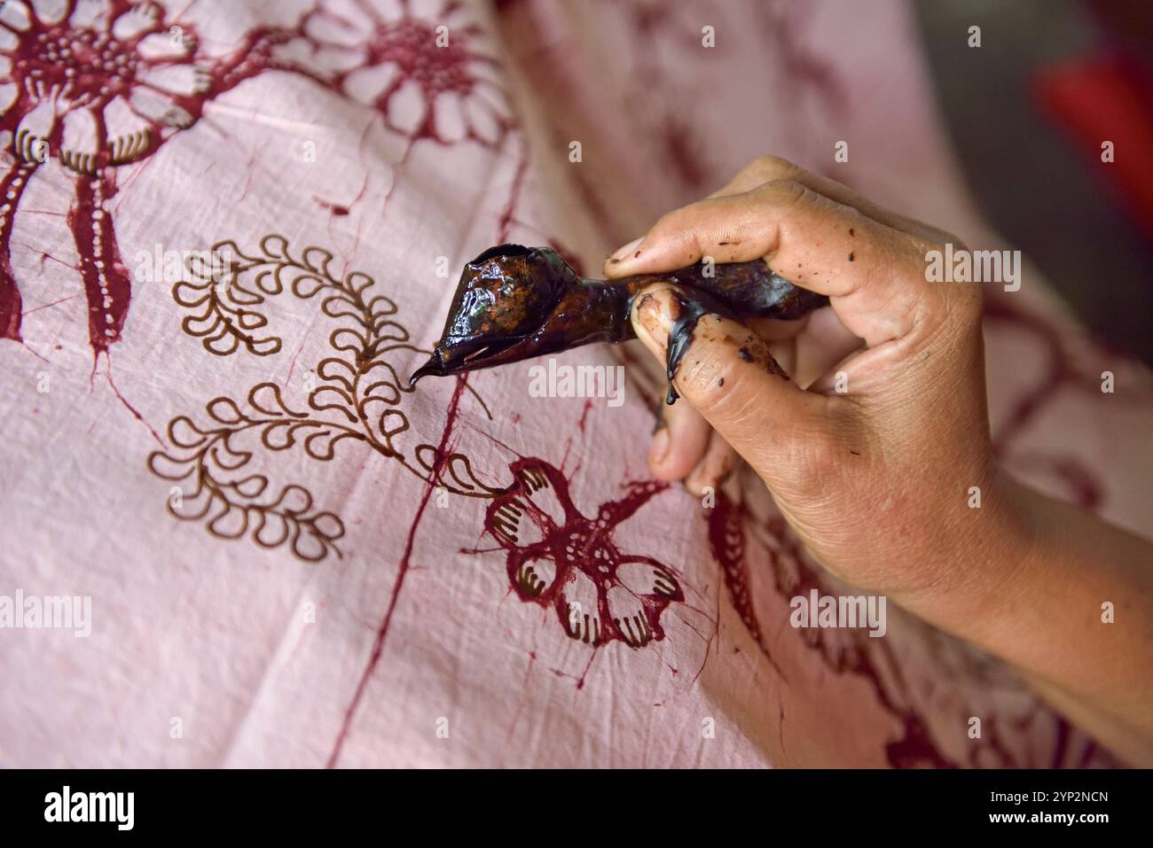 Donna che utilizza uno strumento simile a una penna (cantando) per applicare cera calda liquida per creare un motivo sul tessuto prima della tintura, laboratorio di Kidang Mas Batik House, Lasem Foto Stock