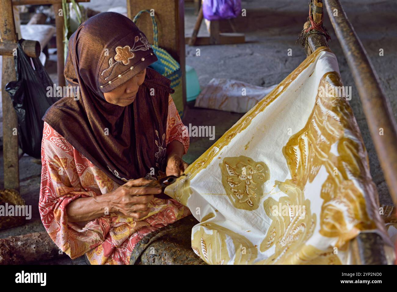 Donna che utilizza uno strumento simile a una penna (cantando) per applicare cera calda liquida per creare un motivo su tessuto senza disegno preliminare, Nyah Kiok batik House, Lasem Foto Stock