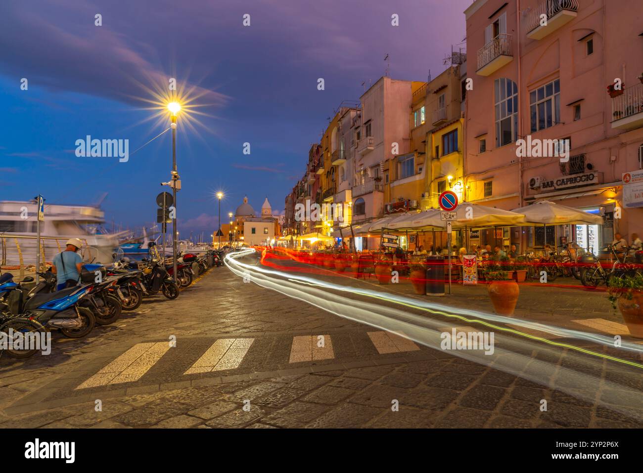 Vista di bar e ristoranti nel porto dei pescatori di Marina grande con le luci al crepuscolo, Procida, Isole Flegrei, Golfo di Napoli, Campania Foto Stock