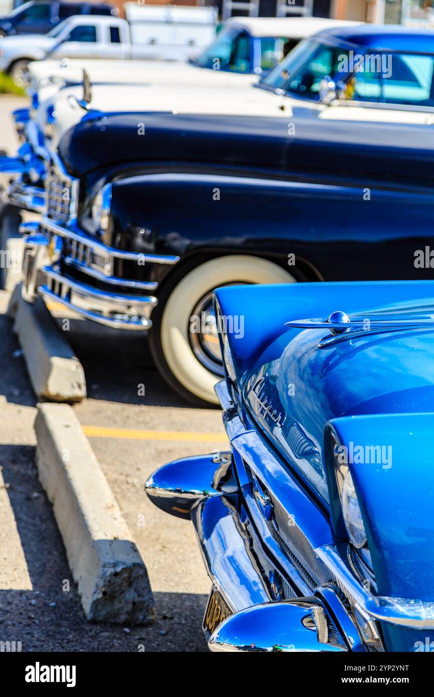 Un'auto blu è parcheggiata accanto a un'auto bianca e a un'auto nera. L'auto blu è la più prominente e ha una finitura lucida Foto Stock