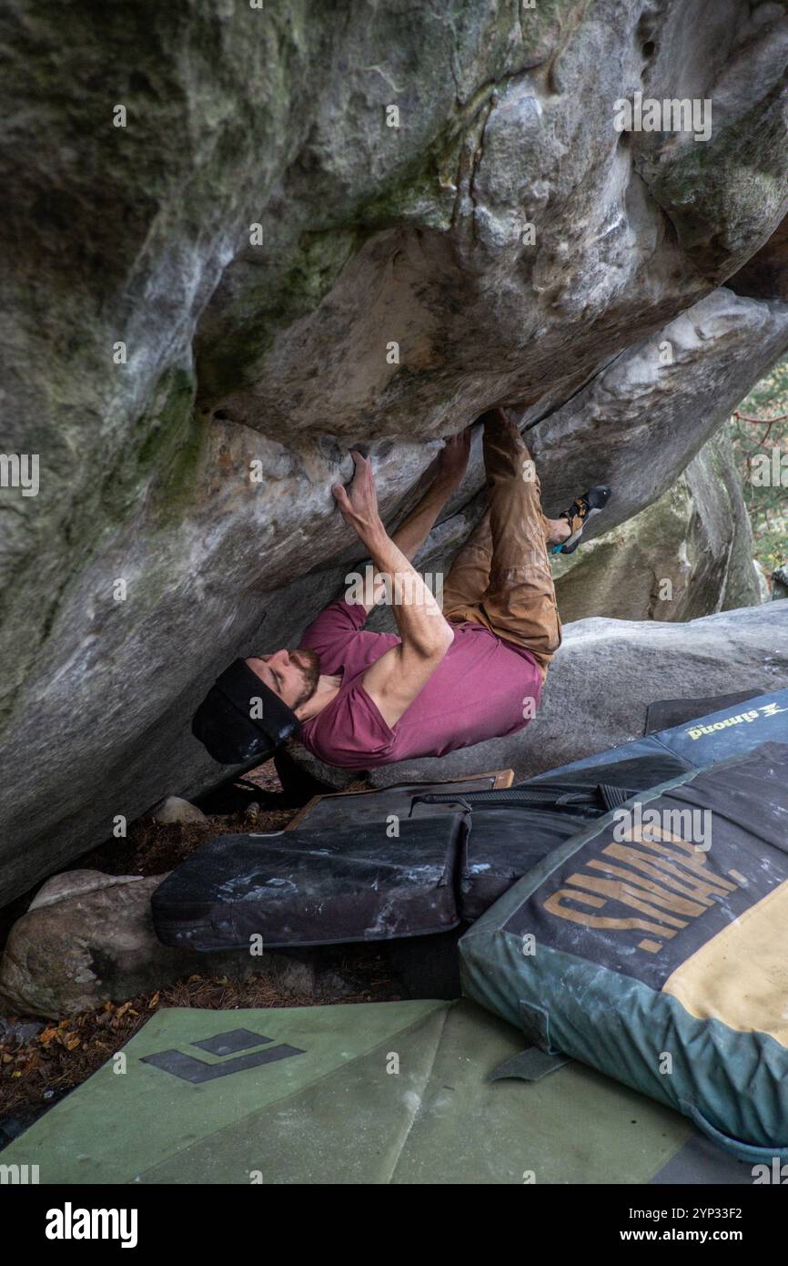 Michael Bunel/le Pictorium - ARRAMPICATA SU BLOCCHI NELLA FORESTA DI FONTAINEBLEAU - 05/01/2016 - Francia/Fontainebleau - due fratelli praticano il bouldering nella foresta di Fontainebleau. Il bouldering comporta l'arrampicata di rocce di altezza inferiore a 8 metri senza l'aiuto di una corda. I materassi, chiamati collisioni, posizionati a terra proteggono dalle cadute. Una persona può essere aggiunta al dispositivo per evitare cadute cattive; lo chiamiamo lo spotter nel gergo dell'arrampicata. Fontainebleau è conosciuta in tutto il mondo per essere la culla del bouldering. Il massiccio forestale di Fontainebleau accoglie 4 milioni di visitatori arrampicati ogni anno Foto Stock
