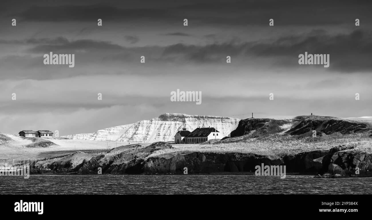 Paesaggio panoramico con montagne costiere innevate sotto il cielo spettacolare. Area di Reykjavik, Islanda. Fotografia in bianco e nero Foto Stock
