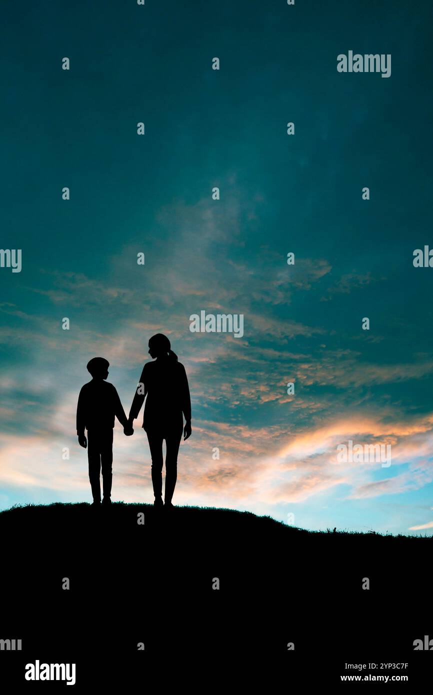 silhouette di madre e figlio mano nella mano, su una cresta al crepuscolo Foto Stock